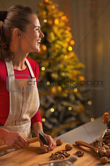 Happy young woman chopping walnuts in christmas decorated kitche