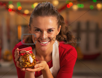 Portrait of happy young housewife showing jar with honey nuts