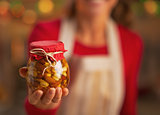 Closeup on young housewife showing jar with honey nuts