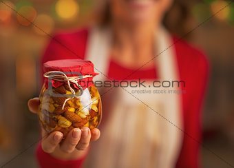 Closeup on young housewife showing jar with honey nuts