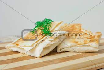 Envelopes of pita with dill on a wooden board