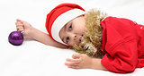 child in santa claus hat lies on bed