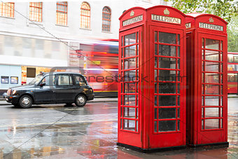 Red Phone cabines in London and vintage taxi.Rainy day.
