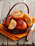 persimmon fruit whole and sliced on a wooden table