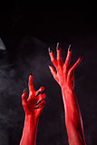 Spooky red devil hands with black nails  