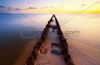 long wooden dike in North sea at sunset