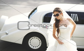 Young bride against limo. Hot summer day.