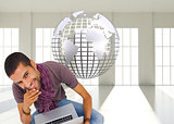 Composite image of thoughtful man sitting on floor using laptop and smiling at camera