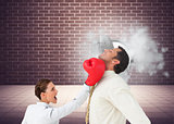 Composite image of businesswoman hitting a businessman with boxing gloves