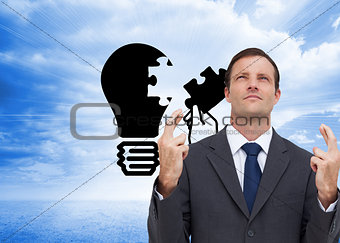 Composite image of serious businessman with fingers crossed is looking up