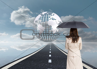 Composite image of rear view of classy businesswoman holding umbrella