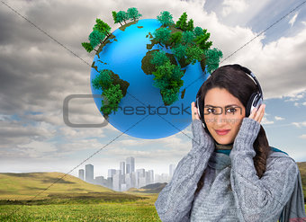 Composite image of beautiful model wearing winter clothes listening to music