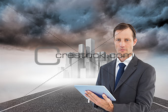 Composite image of serious charismatic businessman holding a tablet computer