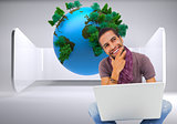 Composite image of thinking man sitting on floor using laptop and smiling