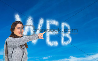 Composite image of smiling brunette wearing winter clothes pointing out