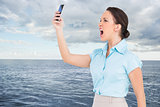 Composite image of angry classy businesswoman yelling at her smartphone