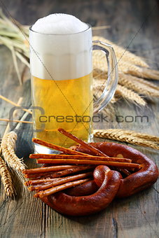 Pretzel, salty sticks and a glass of beer.