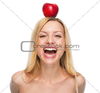 Portrait of smiling teenage girl with apple on head