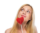 Portrait of happy teenage girl with heart shaped lollypop lookin