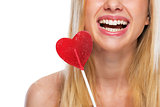 Closeup on smiling teenage girl with heart shaped lollypop