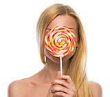 Teenage girl hiding behind lollypop