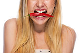 Closeup on teenage girl holding red chili pepper in mouth