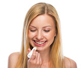 Portrait of happy teenage girl applying hygienic lipstick