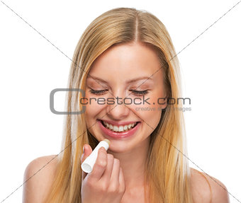 Portrait of happy teenage girl applying hygienic lipstick