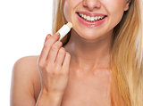Closeup on happy teenage girl applying hygienic lipstick