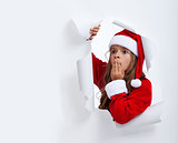 Surprised Santa girl looking through hole in paper