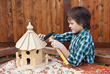 Boy building a bird house - mounting the last roof piece