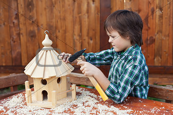 Boy building a bird house - mounting the last roof piece
