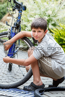 Teenager repairing his bike, changing broken tire