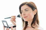 attractive woman in her forties applying makeup to her face