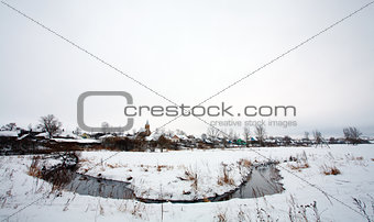 Rural winter landscape with a village and river