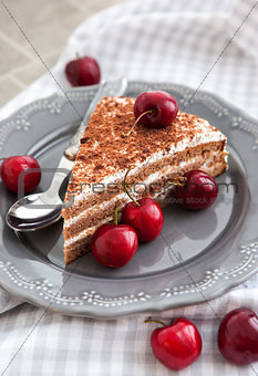 Chocolate cake with cream decorated with fresh cherry