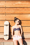 beautiful sexy girl with skateboard poses against wooden wall