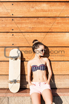 beautiful sexy girl with skateboard poses against wooden wall