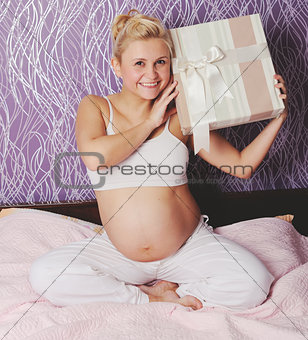 young pregnant woman sitting on bed