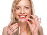 Portrait of happy teenage girl with cup of water and pill