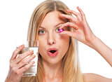 Portrait of teenage girl with cup of water showing pill