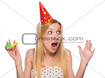 Portrait of surprised teenage girl in cap with party horn blower