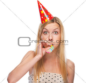 Portrait of teenage girl in cap blowing in party horn blower