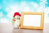 Blank photo frame and christmas snowman on wooden table