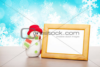 Blank photo frame and christmas snowman on wooden table