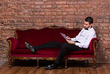Businessman lying on a settee and reading paperwork