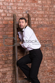 Terrified man trapped at the top of a ladder