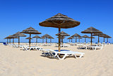Parasol and sun loungers on the beach sand, Algarve.