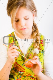 Young girl painting an egg