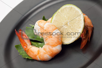 Shrimp with lime on black plate